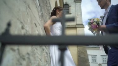 Mavi takım elbise ve renkli gül düğün buketi yakışıklı şık damat büyüleyici gelini güzel gülümseme ile geliyor ve onu öpüyor.