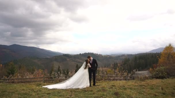 Paseo romántico de bodas en las hermosas montañas doradas. Vista completa de los recién casados elegantes abrazándose tiernamente . — Vídeo de stock