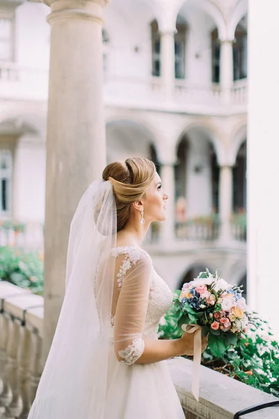 Невеста со свадебным букетом проводит время на старом балконе . — стоковое фото
