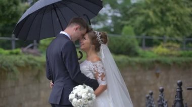 Şefkatle yağmur şemsiyesi altında burun sürtme mutlu muhteşem yeni evli çiftin varoluş portre.