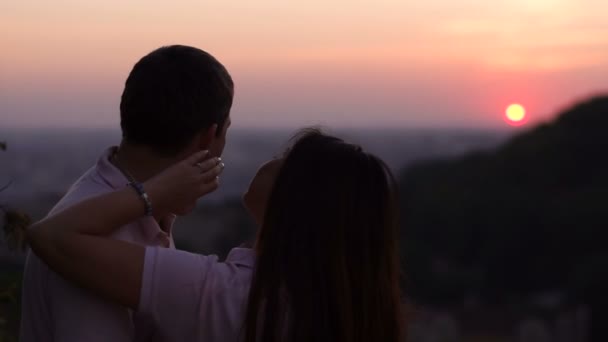 Ambiente romántico. La mujer está tiernamente tocando la cara de su novio mientras disfruta de la hermosa puesta de sol roja en las montañas. Retrato trasero . — Vídeos de Stock