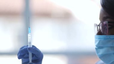 Yakın çekim yan portresi Afrika doktor gözlük ve tıbbi maske aşı şırınga tutarak.