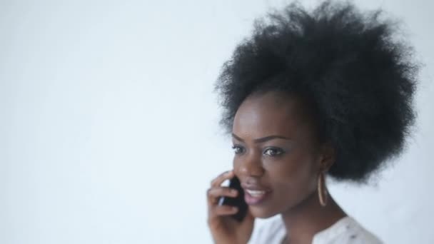 Retrato de cerca del atractivo gerente de la oficina africana con una bonita sonrisa hablando en el teléfono móvil . — Vídeo de stock