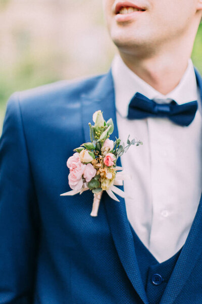 The boutonniere of roses on the jacket of the groom.