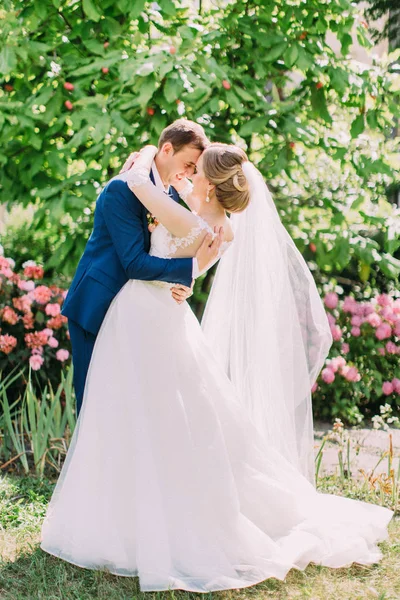 Abraços alegres recém-casados no lindo jardim. — Fotografia de Stock