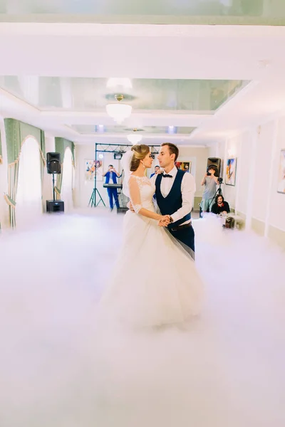 Os recém casados estão a aperfeiçoar a sua primeira dança na pista de dança fumegante. . — Fotografia de Stock