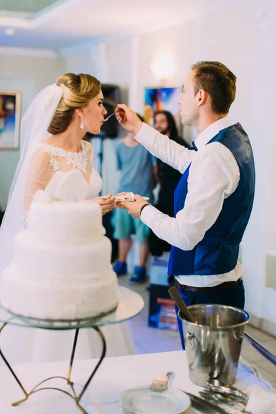 O noivo está alimentando a noiva com o bolo de casamento . — Fotografia de Stock