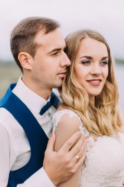 Gevoelige portret van de zijde van de bruidegom knuffelen de mooie bruid terug. — Stockfoto