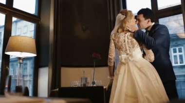 Arkadan Görünüş şefkatle sarılma ve öpüşme lüks restoranda yeni evli genç zarif çift.