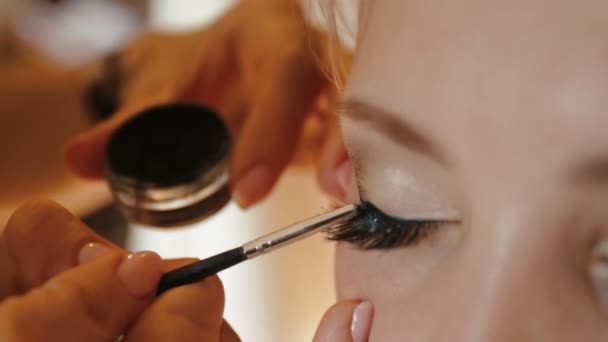 Maquillaje artista está haciendo el maquillaje para novia encantadora. Ella está pintando los ojos de gato. Preparación de boda . — Vídeo de stock