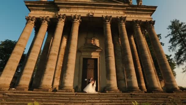Charmant couple élégant de jeunes mariés danse et s'embrasse près de l'ancien bâtiment de style baroque . — Video
