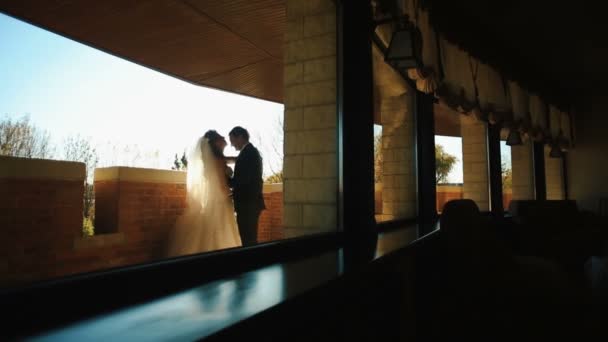 Charmant couple de jeunes mariés s'étreint tendrement sur la terrasse. La mariée embrasse son amant dans la tête . — Video