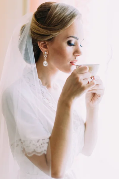 Närbild sida porträtt av bruden dricka te nära fönstret. — Stockfoto