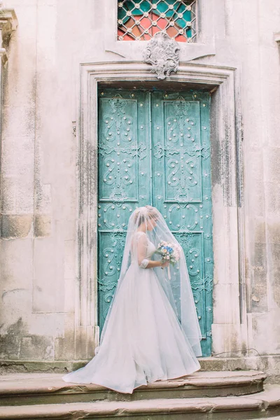 A menyasszony mellett a fátylat a sze csokor gazdaság, és az ajtó melletti állandó hosszúságú oldalnézetből. — Stock Fotó