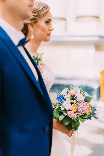 Retrato lateral de la novia sosteniendo el colorido ramo durante la ceremonia de la boda . —  Fotos de Stock