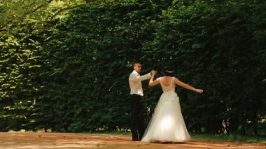 Büyüleyici yeni evli çiftin güzel yeşil parkta dans. Yakışıklı damat onu yukarıya ve iplik yuvarlak havaya kaldırma.