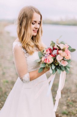 Varoluş yan Çar buket sahilde tutan sarışın gelin portresi.