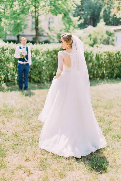 La vue arrière de la mariée à l'arrière-plan flou du marié. Emplacement du jardin . — Photo