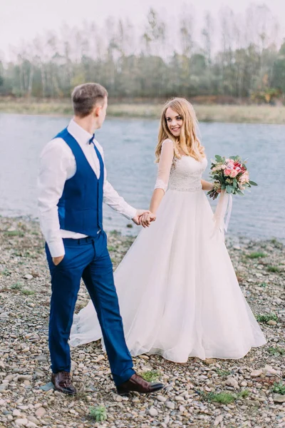 Volledige weergave van de pasgetrouwden hand in hand tijdens een wandeling langs het strand. — Stockfoto