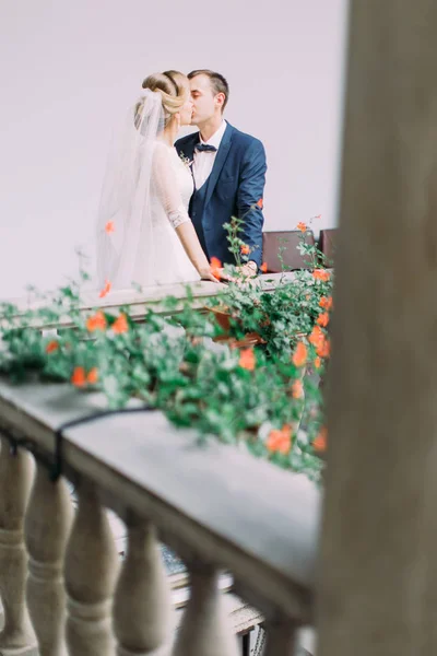 Прекрасний балкон з квітами і цілує молоду пару на ньому . — стокове фото