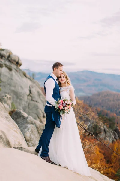 拥抱新婚夫妇站在岩石上, 享受 naturescape 的侧面视图. — 图库照片