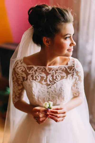 Känsliga sidan porträtt av den vackra bruden holdign boutonniere och tittar åt sidan. — Stockfoto