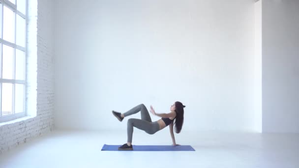 Jonge atletische Sportvrouw in sportkleding is permanent op de handen en het verhogen van haar been aan de hand in witte studio. 4 k-beeldmateriaal. — Stockvideo