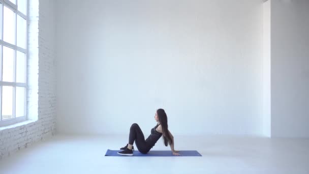 Exercices sportifs pour débutants. La femme sportive se réchauffe en se tenant debout dans la pose du pont et en levant les mains sur les côtés dans un studio blanc. 4k . — Video