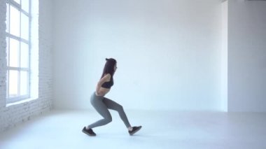 Yeni başlayanlar için kardiyo için Tutorials. Sportif esmer eğitmen beyaz Studio yürüyen lunges yaparak ısınmaya başladı. 4k.