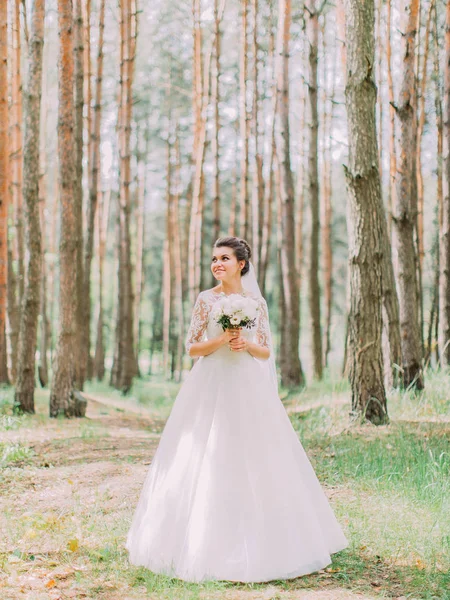 Fullängds utsikt över charmiga bruden med bröllop bukett tittar åt sidan i skogen våren. — Stockfoto