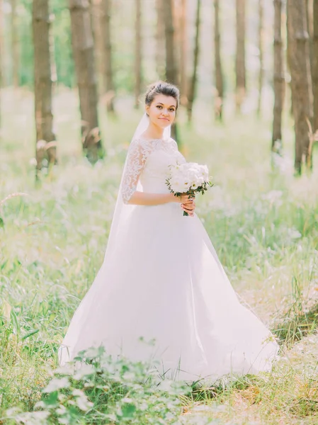 Der Spaziergang der wunderbaren glücklichen Braut entlang des grünen Waldes. — Stockfoto
