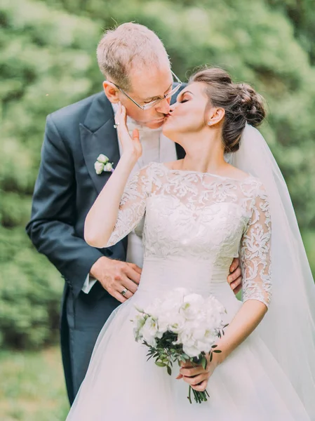 Çiçek açan bahçede öpüşme neşeli yeni evliler varoluş yaz fotoğrafı.