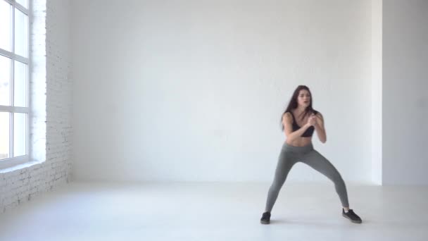 Mladá hubená trenér provádí chodící squatu v bílém studio. 4k. — Stock video