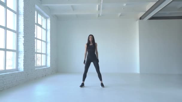 Mujer de fitness deportivo en ropa deportiva está haciendo sentadillas en el estudio blanco. Imágenes de 4k . — Vídeos de Stock