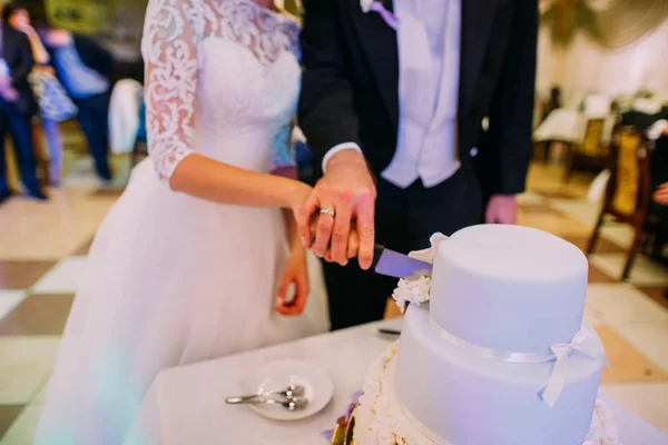 新婚夫婦の手は、ウェディング ケーキの最初の作品を切っています。. — ストック写真