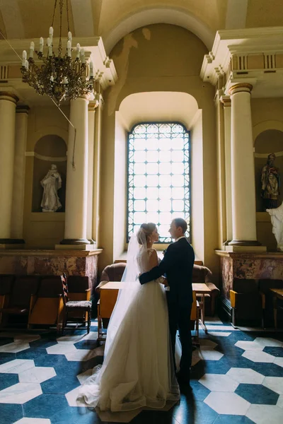 Abrazando a los recién casados en la antigua iglesia durante la ceremonia de casamiento . —  Fotos de Stock