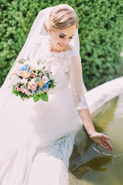 Primo piano vista laterale della bella sposa che gioca con l'acqua in fontana . — Foto Stock