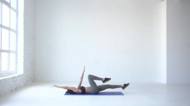 Genç atletik kız bisiklet egzersizi beyaz Studio yaparak ısınmaya başladı. 4 k görüntüleri.