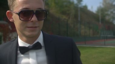 Sevimli gülümseyen gelin onun yakışıklı damat güneş gözlüğü için geliyor. Şefkatle öpüşme ve çiçek açan bahçede sarılma.