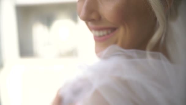 Retrato lateral de cerca de la maravillosa novia en velo con encantador maquillaje y sonrisa posando a la cámara . — Vídeos de Stock