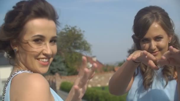 Retrato de dos damas de honor con encanto en vestidos azules bailando y posando en la cámara en el jardín soleado floreciente . — Vídeo de stock