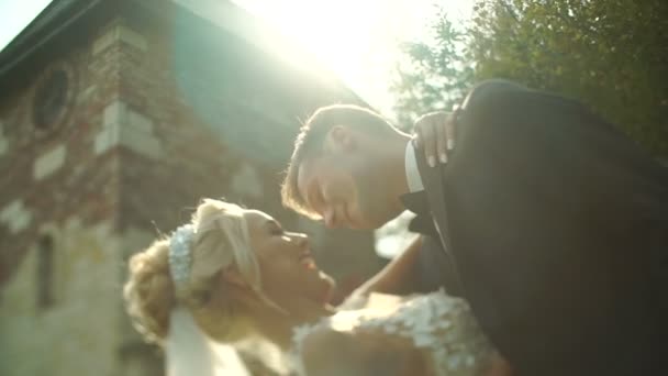 Beijar casal de recém-casados encantadores no jardim florescente durante o pôr do sol. Retrato de close-up . — Vídeo de Stock