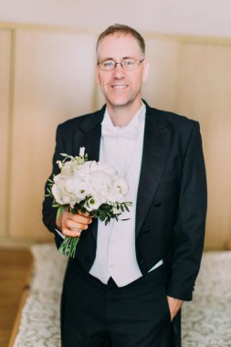 Neşeli damat beyaz peonies düğün bouque tutar.