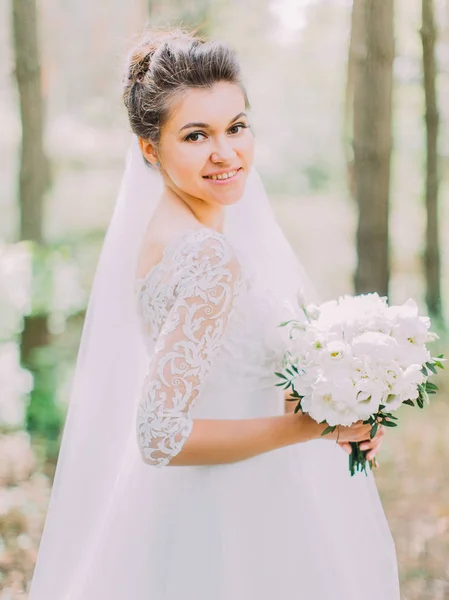 Ritratto di mezza lunghezza della sposa allegra con il mazzo nuziale di peonie. La posizione della foresta . — Foto Stock