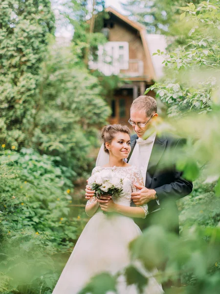 Чутливий портрет нареченого, що обнімає наречену назад у зелений сад . — стокове фото