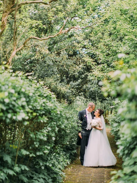 Yeni evliler yeşil bahçe boyunca huzurlu yürüyüş.