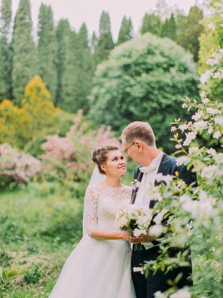 Portrait sensible des jeunes mariés souriants passant du temps dans le jardin en fleurs . — Photo