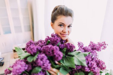 Leylak gülümseyen güzel gelinin elinde büyük bir buket.