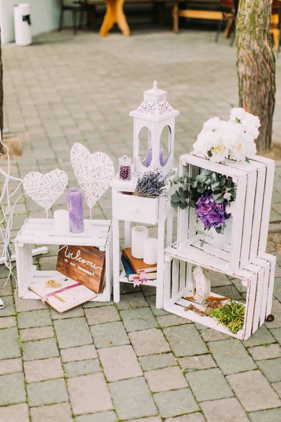 Vista de perto da composição encantadora do casamento das arquibancadas de velas vintage e caixas decoradas com flores e corações artesanais . — Fotografia de Stock