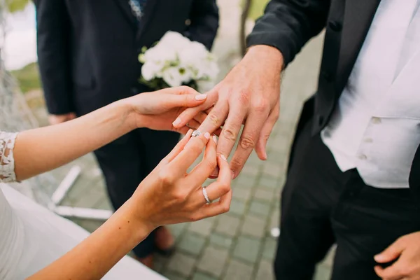 La vista de cerca de las manos de la novia poniendo el anillo de bodas en el dedo del novio . — Foto de Stock